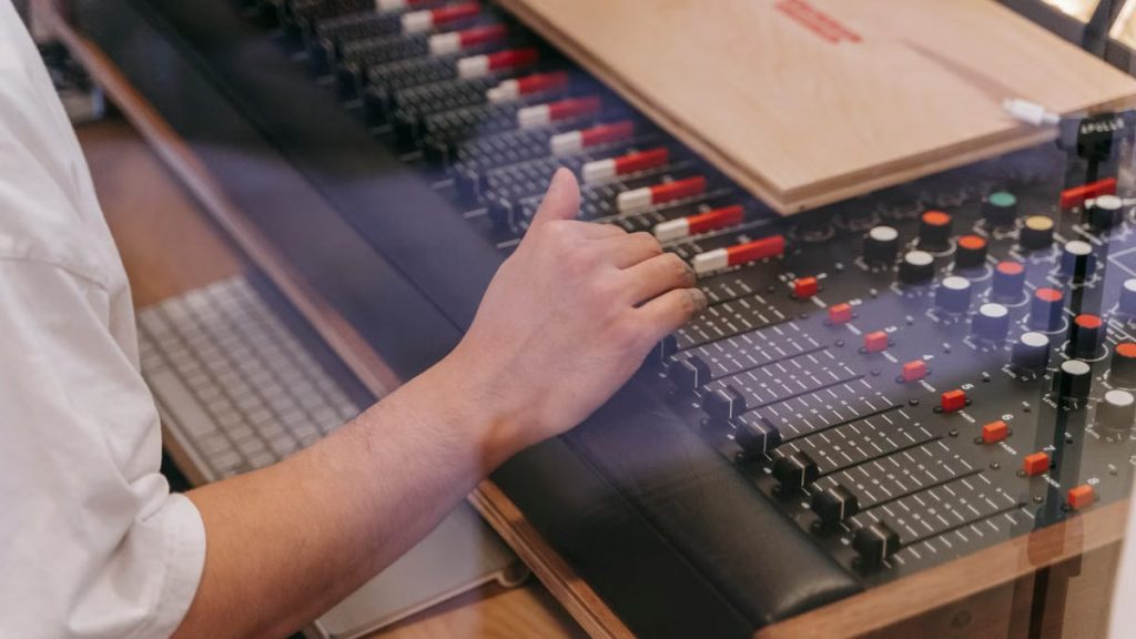 Close-up of an audio engineer's hand adjusting a mixing console in a recording studio.